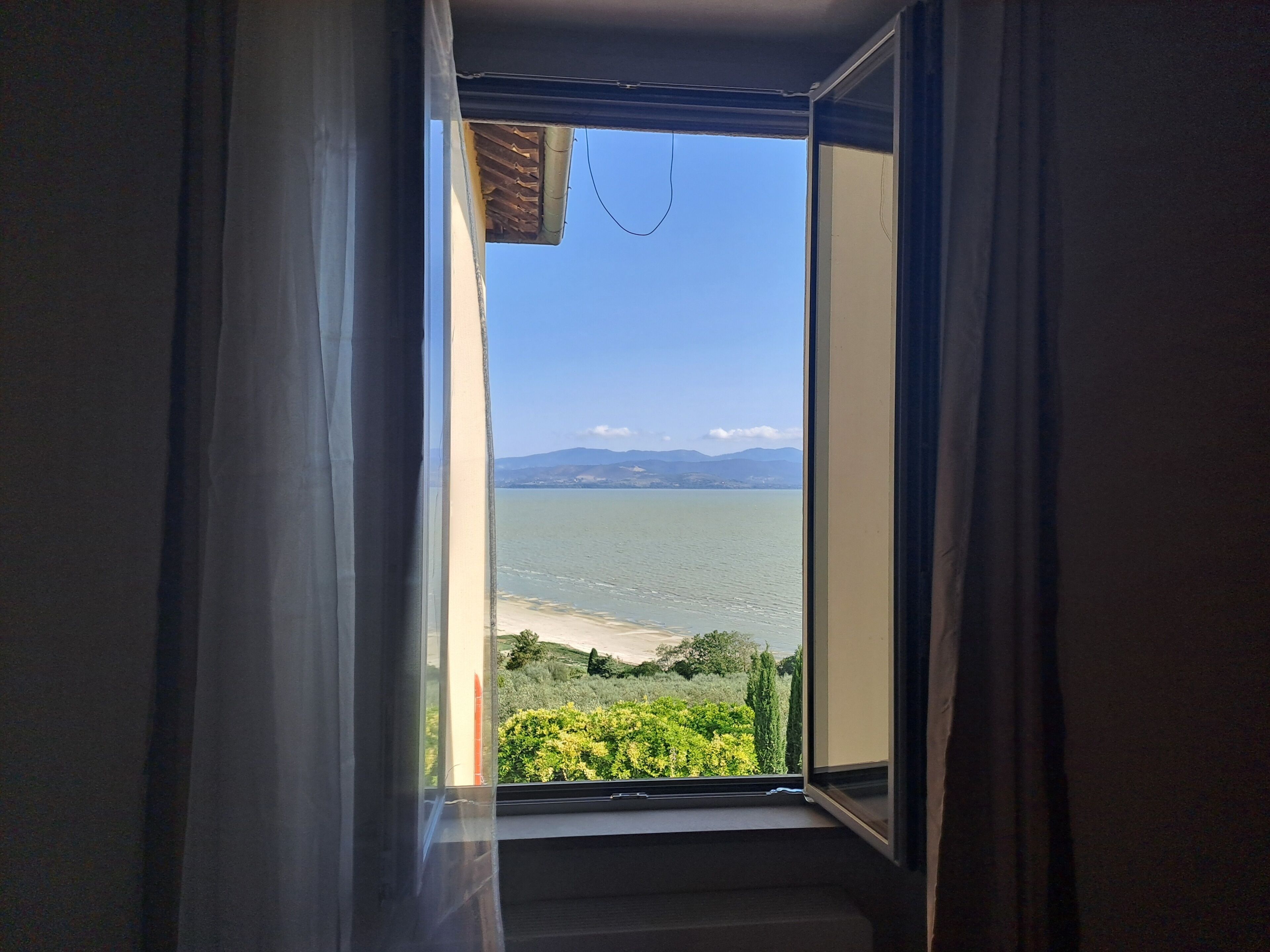 Una stanza con un'ampia finestra che si affaccia su una distesa d'acqua e una costa lontana.