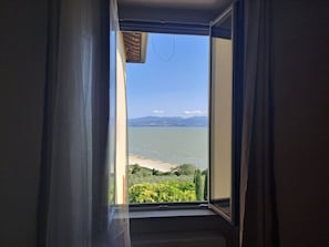 Una habitación con un ventanal grande que da a una masa de agua y una costa lejana.