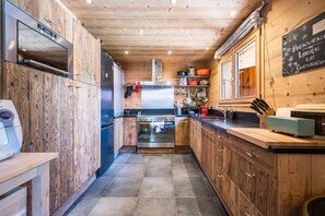 Eine kompakte Küche mit Holzschränken, einem Edelstahlkühlschrank und einem eingebauten Backofen.