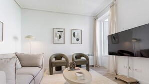 A modern living room with a sofa, two armchairs, a coffee table, a flat-screen TV, and artwork on the wall. - Genteel Home Reina Sofia IV (Madrid)