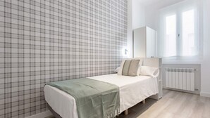 A bedroom with a bed, a radiator, a window, and a wall with a plaid pattern. - Genteel Home Reina Sofia IV (Madrid)
