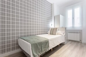 Ein Schlafzimmer mit einem Bett, einem Heizkörper, einem Fenster und einer Wand mit Karomuster.