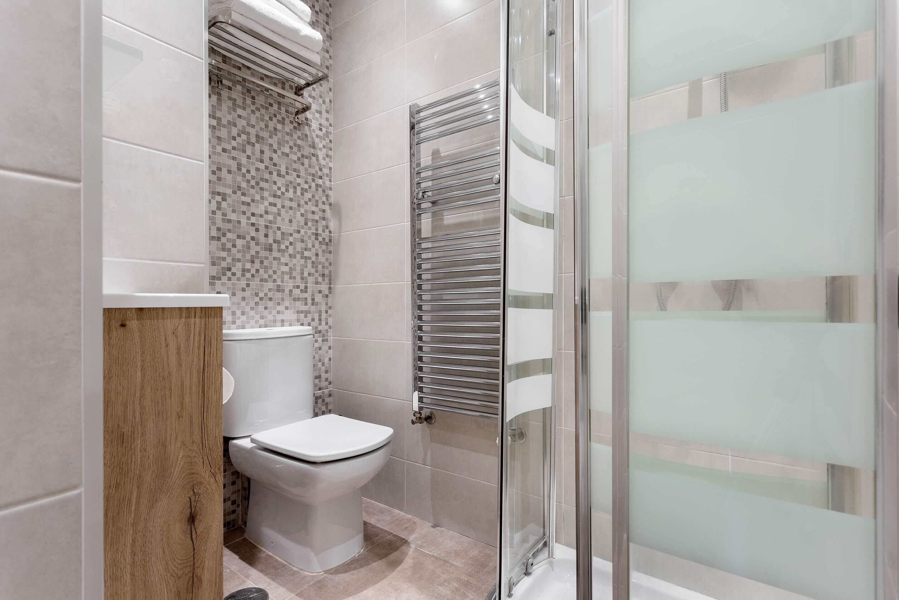 A modern bathroom with a toilet, a shower enclosure, and a glass shower door.
