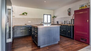A modern kitchen with a central island, dark cabinetry, and a red refrigerator. - 180-square-meter house · Pool table · Air conditioning · Garden · Tours (Chambray-lès-Tours)