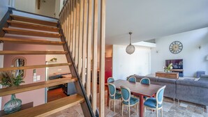 A modern interior with a wooden staircase, a dining area with blue chairs, and a living room with a sofa and TV. - 180-square-meter house · Pool table · Air conditioning · Garden · Tours (Chambray-lès-Tours)