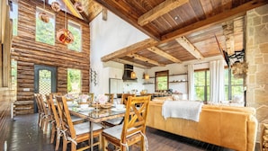A rustic interior with a wooden dining table, chairs, a sofa, and a stone wall. - Cloud Haven Retreat | Views, Hot Tub + Games (Gatlinburg)