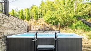 A hot tub with steps leading up to it, surrounded by a stone wall and a wooden fence. - Cloud Haven Retreat | Views, Hot Tub + Games (Gatlinburg)