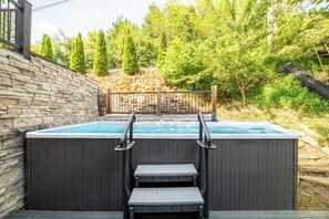 A hot tub with steps leading up to it, surrounded by a stone wall and a wooden fence. - Cloud Haven Retreat | Views, Hot Tub + Games (Gatlinburg)