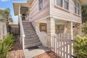 A two-story house with a white picket fence, a wooden staircase, and a brick pathway leading to the entrance. - Little Sister Carriage House l Walk to DNTN (St. Augustine)