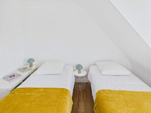 A room with two beds, a small table with a lamp, and a book on the table. - House for 6, pool, boules & foosball (Plomeur)