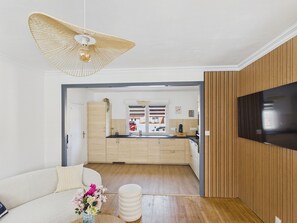 Een moderne keuken met houten kastjes, een zwart aanrecht en een hangende lamp.