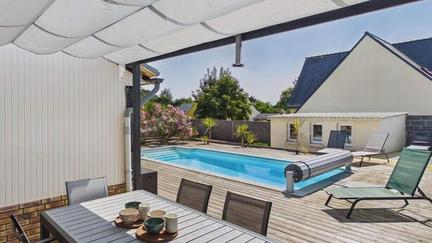 Zona de piscina exterior amb terrassa coberta, gandules i taula amb safates.