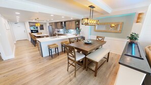 A modern kitchen with a central island, wooden dining table, and bar area. - Stunning & Renovated 2 Bedroom ST 2105 (Destin)