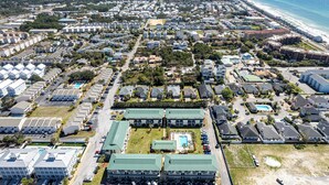 An aerial view of a coastal residential area with a large hotel featuring a swimming pool and multiple parking spaces. - Spacious + In A Great Location Sandprints B1 (Miramar Beach)