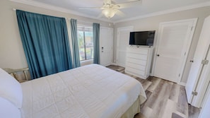Ein Schlafzimmer mit Bett, Deckenventilator, Fernseher und Kleiderschrank.
