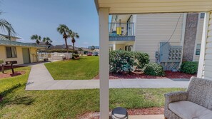 A residential area with a grassy lawn, a pathway, and a building with a balcony. - Spacious + In A Great Location Sandprints B1 (Miramar Beach)
