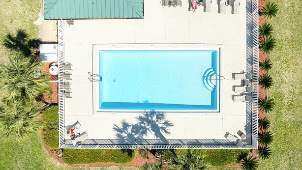 An aerial view of a swimming pool with surrounding lounge chairs and palm trees. - Spacious + In A Great Location Sandprints B1 (Miramar Beach)