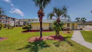 A hotel with a well-maintained lawn, palm trees, and a clear sky. - Spacious + In A Great Location Sandprints B1 (Miramar Beach)