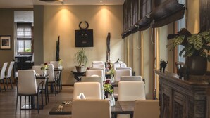 Un espace repas comprenant plusieurs tables et chaises, une cheminée et une grande fenêtre.