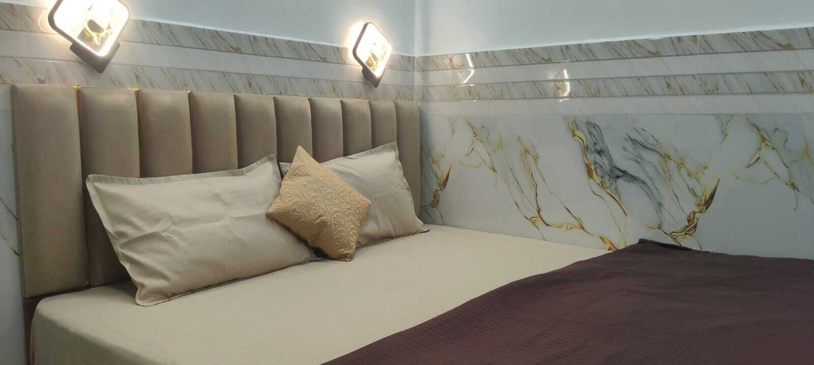 A hotel room with a bed, a headboard, and a wall with a marble pattern.