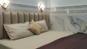 Habitación de hotel con cama, cabecera y pared con diseño de mármol.