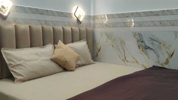 A hotel room with a bed, a headboard, and a wall with a marble pattern.