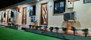 Une rangée de pièces équipées de climatiseurs, une porte à motifs et de petites plantes le long du chemin.