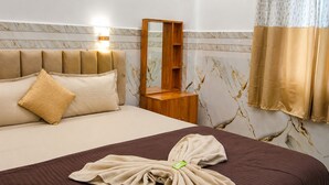 A hotel room with a bed, a bedside table, a mirror, and a window with curtains. - Ave maria Luxury Room and Apartment  (Colva)