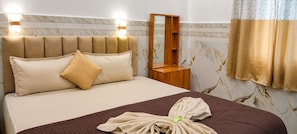 Habitación de hotel con cama, mesita de noche, espejo y ventana con cortinas.