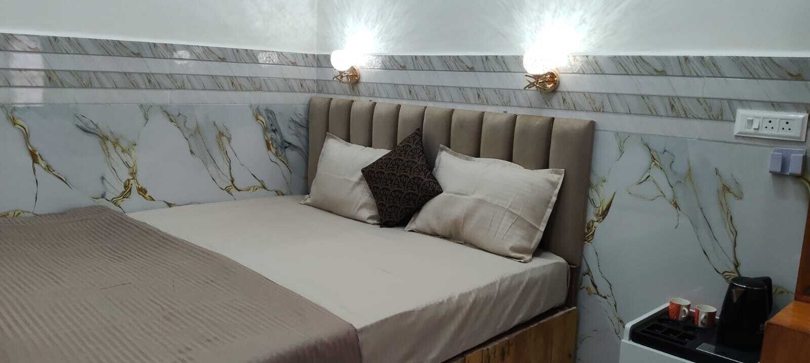 Una cama con cabecera, dos lámparas fijadas a la pared y un enchufe en la pared.