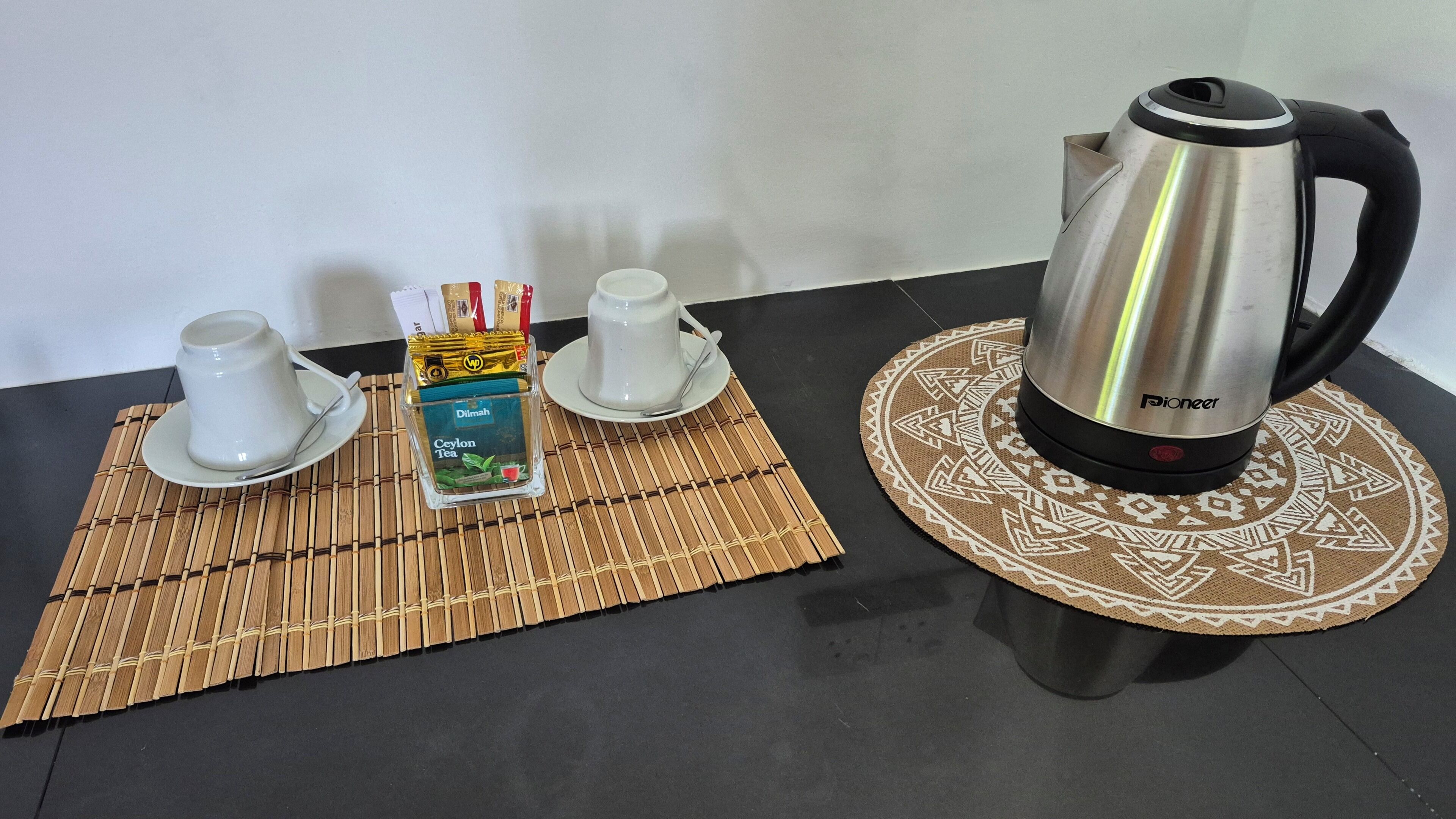 A table with a tea set, a box of tea, and a kettle.