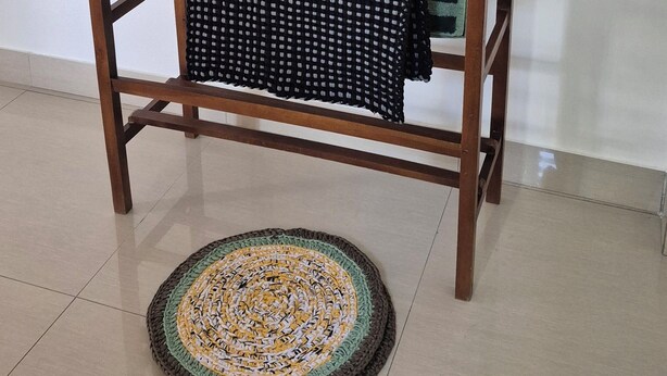 A wooden drying rack with three towels and a patterned rug on a tiled floor. - NATIVE SOULS Beach Hotel (Induruwa)