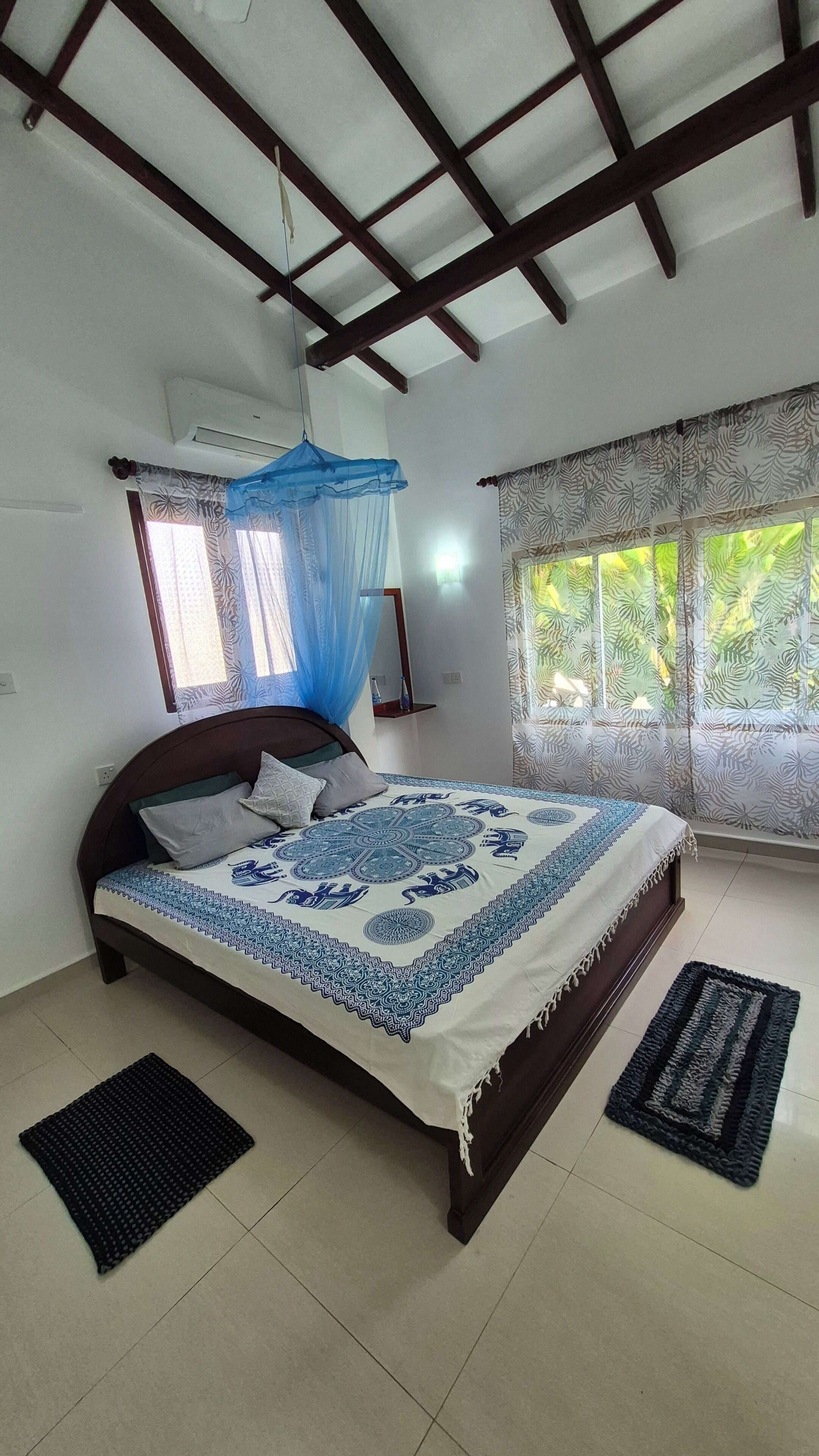 A bedroom with a bed, a ceiling fan, a window with curtains, and a bedside table.