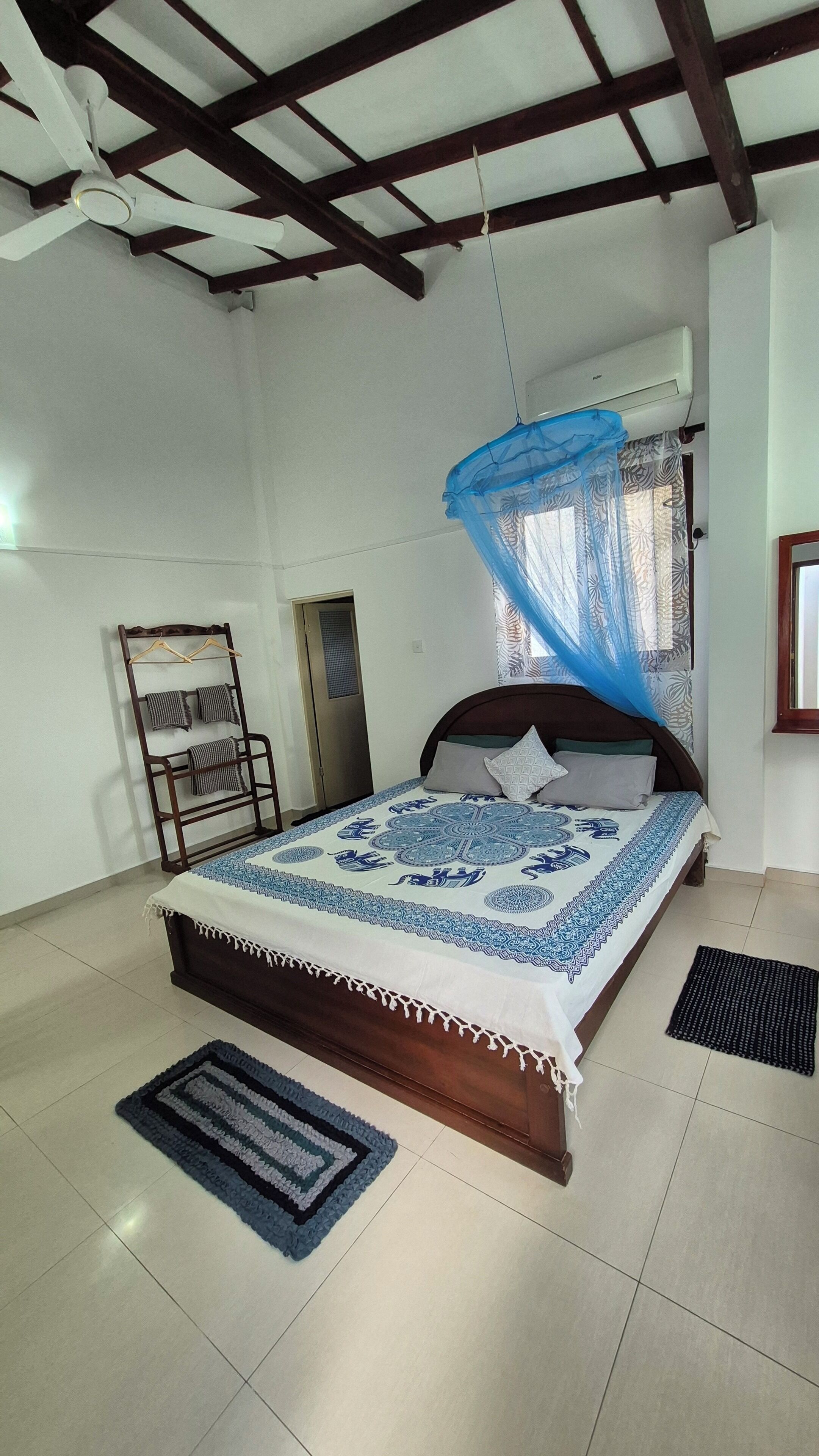 Un dormitorio con cama, una silla colgante, aire acondicionado instalado en la pared y una ventana con cortina.