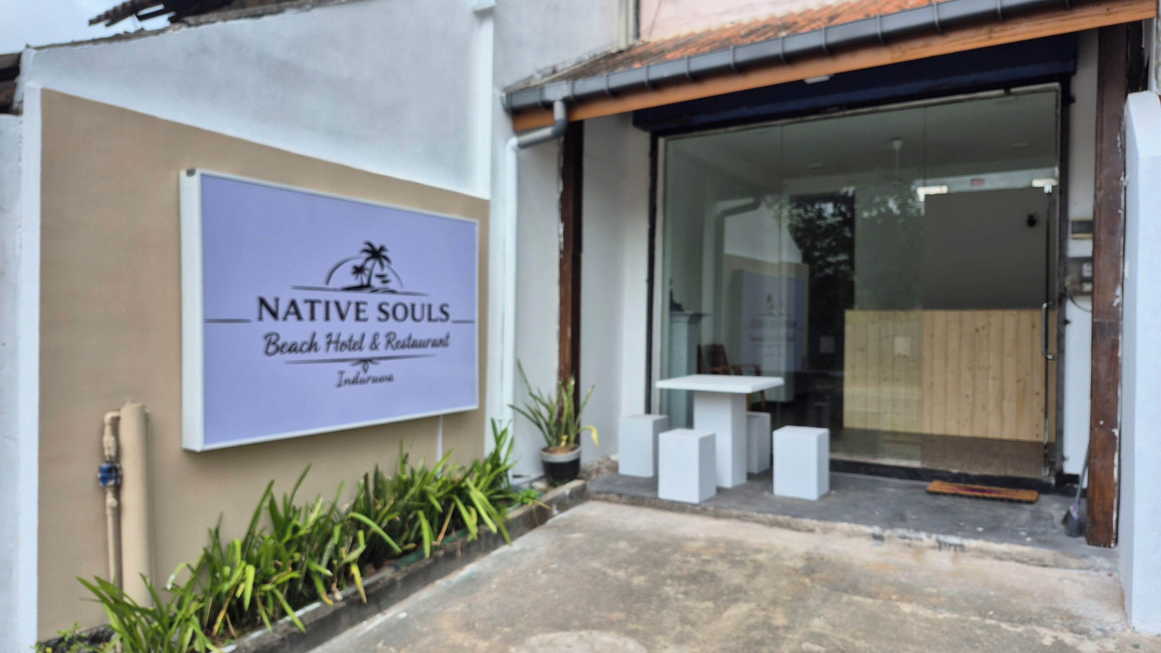 Señal para el hotel y restaurante Native Souls Beach, con entrada despejada y un pequeño espacio de mesas al aire libre.