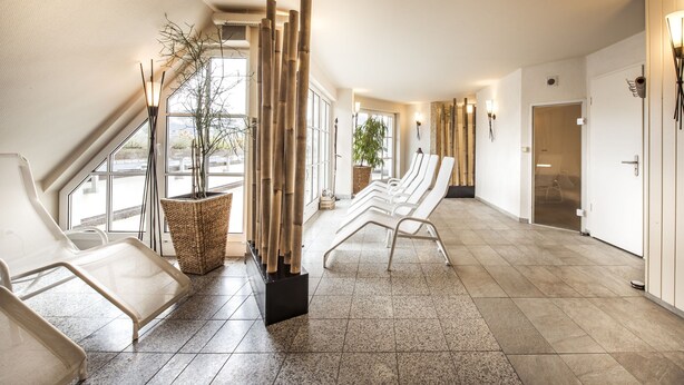 Et moderne venteområde med loungesæde, en bambus skærm og et stort vindue der giver naturligt lys.