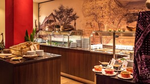 Un espace buffet avec une carte affichée au mur, une statue de girafe et divers plats proposés.