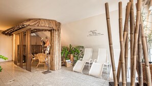 Un espace de détente avec une structure à toit de chaume, des chaises longues blanches et une sculpture en bambou.