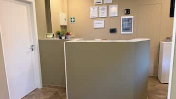 Un'area di accoglienza con una reception, una porta e un muro con diversi cartelli e avvisi.