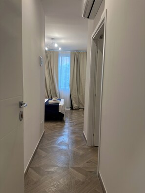 Passadís d'hotel amb un llit, una porta i un aparell d'aire condicionat.