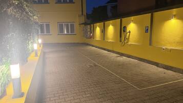 A paved outdoor area with a yellow building, a fire hose reel, and a parking sign.