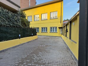 A yellow building with multiple windows and a paved courtyard. - Hotel Link Rho - JCUBE HOTELLERIE (Rho)