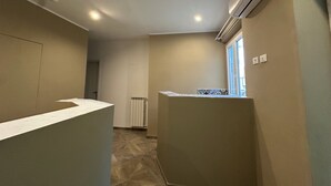 Una camera d'albergo con angolo cottura, termosifone e finestra con persiane.