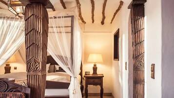 Una camera da letto con un letto a baldacchino, un comodino con una lampada e una porta in legno con un pannello decorativo.