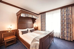 A hotel room with a large bed, wooden headboard, two bedside tables, and a window with floral curtains. - Memorable Lake Sorpe Escape with Dining & Relaxation (Sundern (Sauerland))