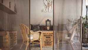 A room with wicker furniture, a wall-mounted lantern, and a sign indicating Kolkata as a port of destination. - Modern Escape Near Badehaus Norderney & Weststrand Beach l 2 Units (Sundern (Sauerland))