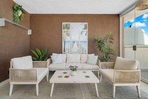 Quarto com sofá, duas poltronas, mesa de centro e uma janela grande com vista para um cais.