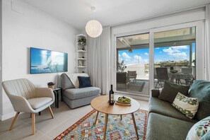 A modern living room with a sofa, armchairs, a coffee table, and a TV. - Rooftop* Terrace*pool*parking* Town view (Estepona)