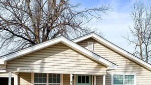 Une maison de plain-pied avec un porche à l’avant, une boîte aux lettres et le numéro « 409 » sur la porte.