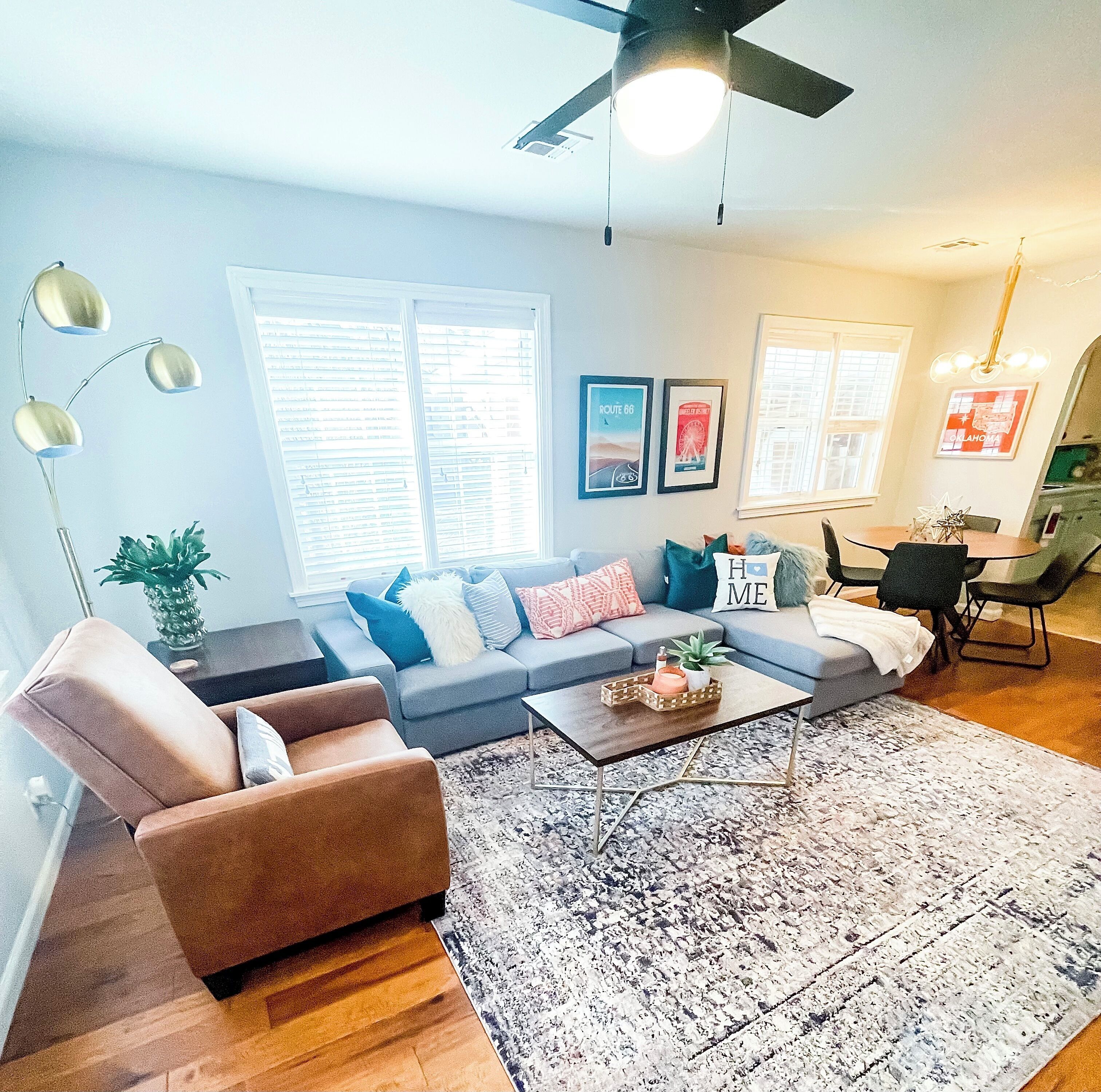A modern living room with a sofa, armchair, coffee table, and a ceiling fan.